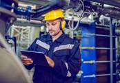Dedicated Factory Worker Standing Next To Boiler And Holding Tablet. Worker  Is Dressed In Protective Uniform, Having Hardhat And Antiphons. - Aitex